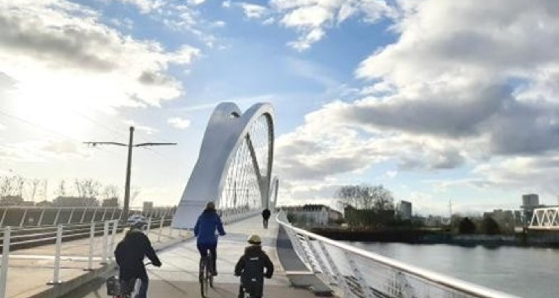 Zwei Kinder und eine Erwachsene Person fahren mit dem Fahrrad über die Trambrücke in Kehl