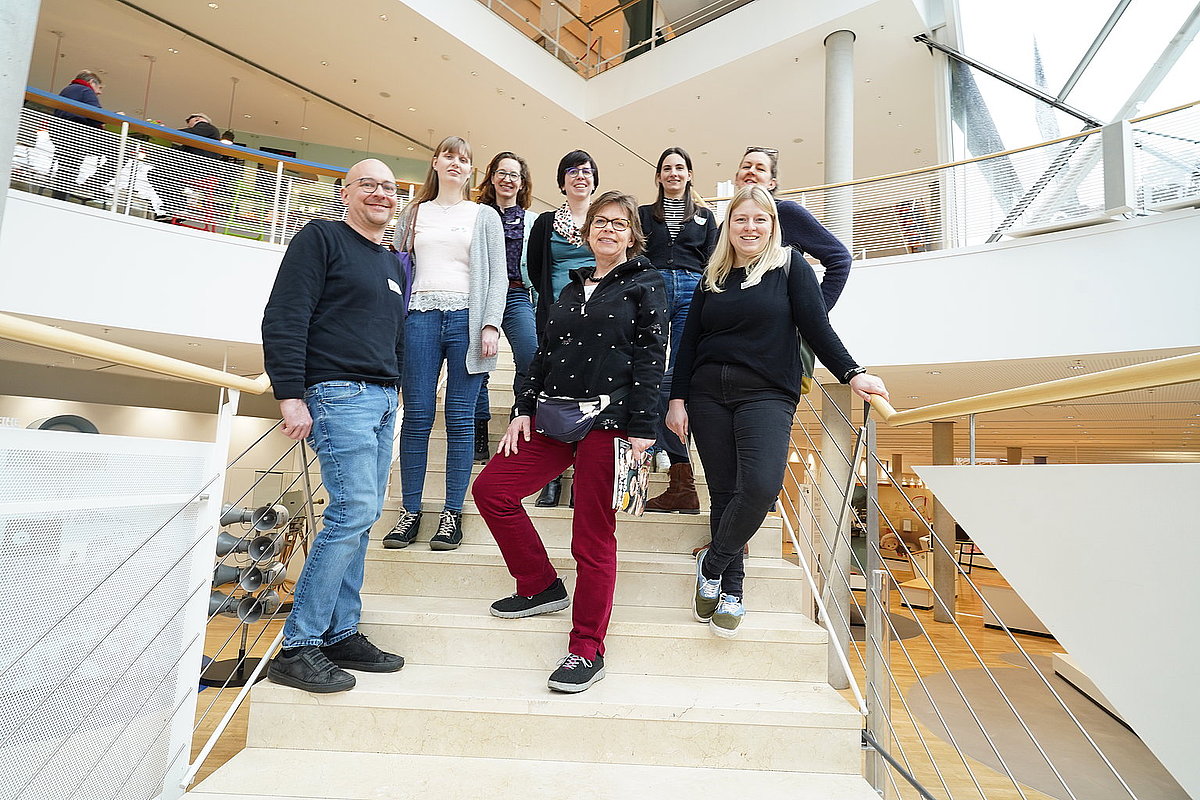 kleine Gruppe steht auf einer Treppe in großem Gebäude
