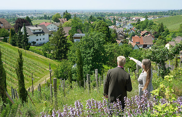 zwei personen stehen auf einer Anhöhe vor einer Stadt