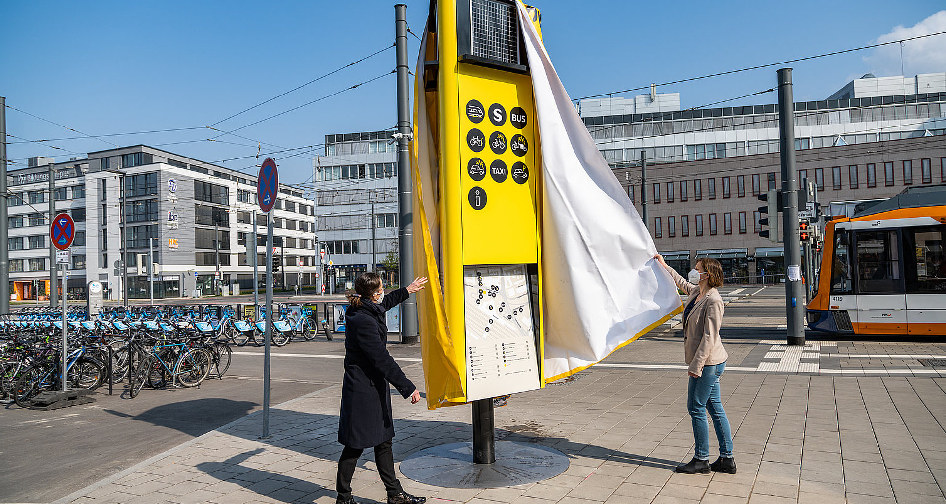 Zwei Frauen enthüllen eine gelbe Mobilitätssäule.