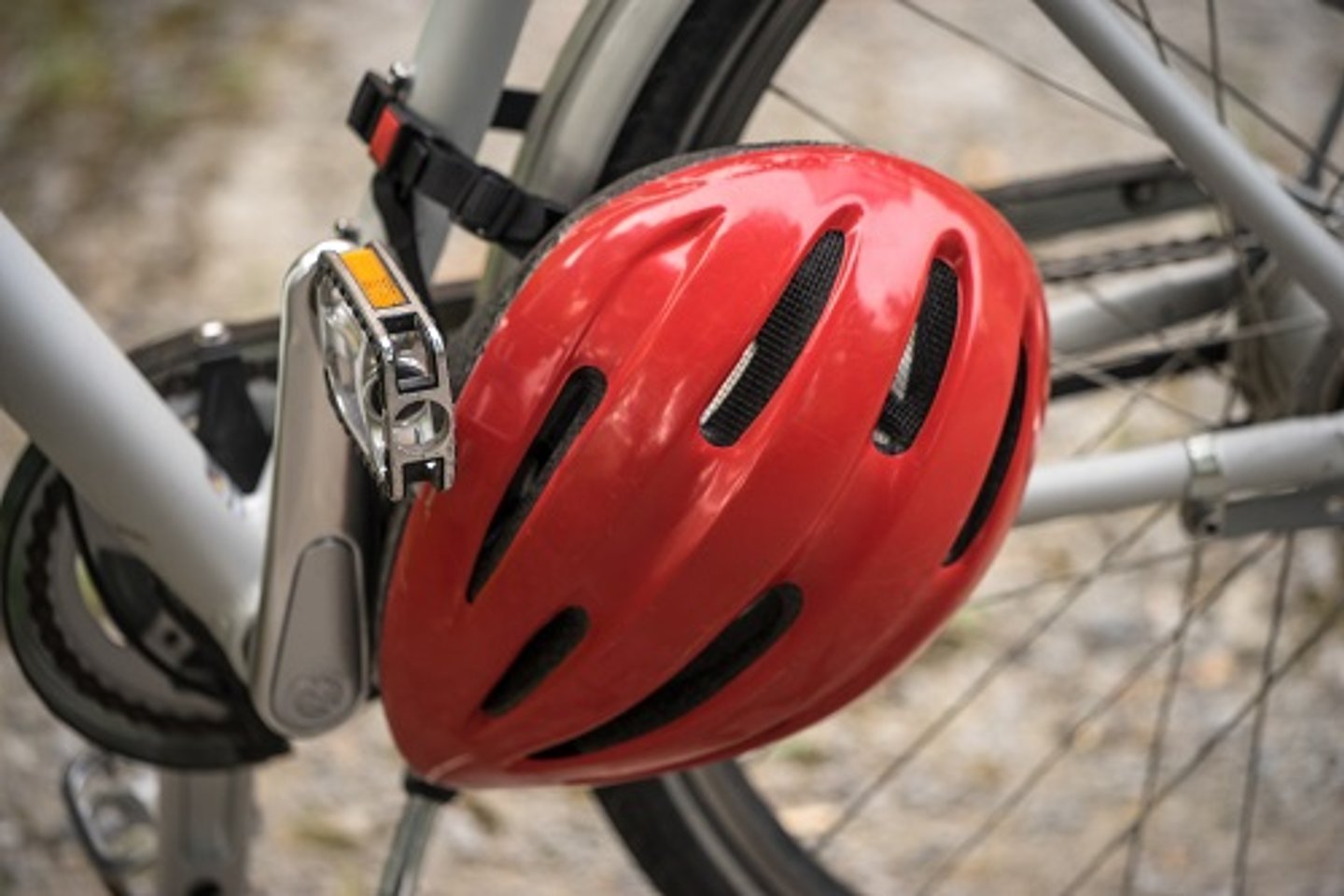 Ausschnitt silberner Fahrradrahmen und Tretlager mit am Rahmen befestigtem roten Helm