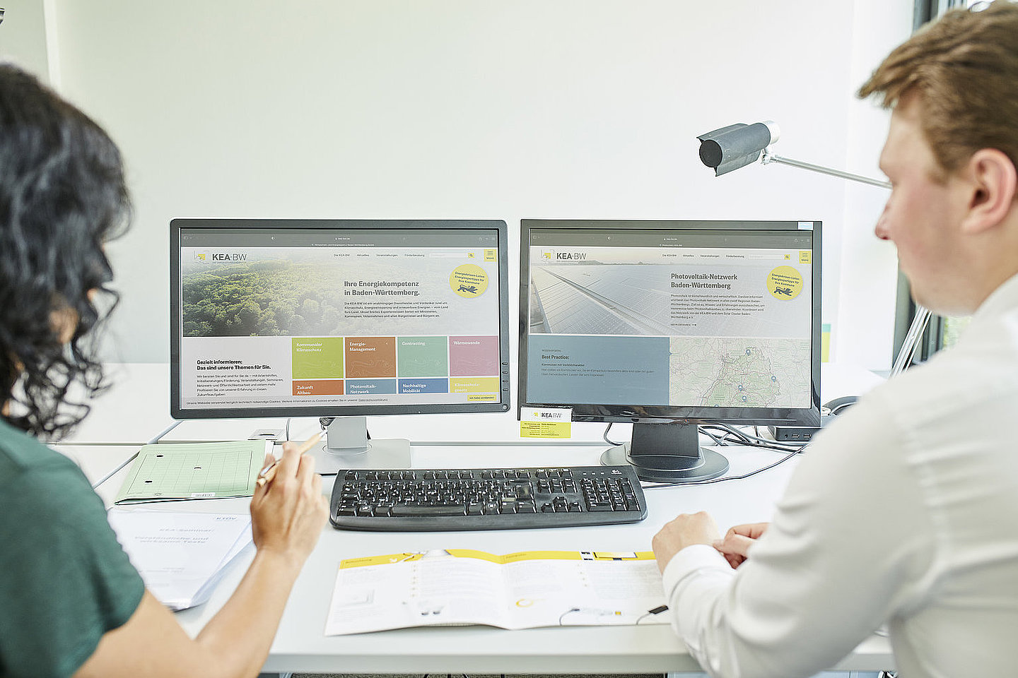 2 Personen sitzen vor dem Laptop-Bildschirm und diskutieren.