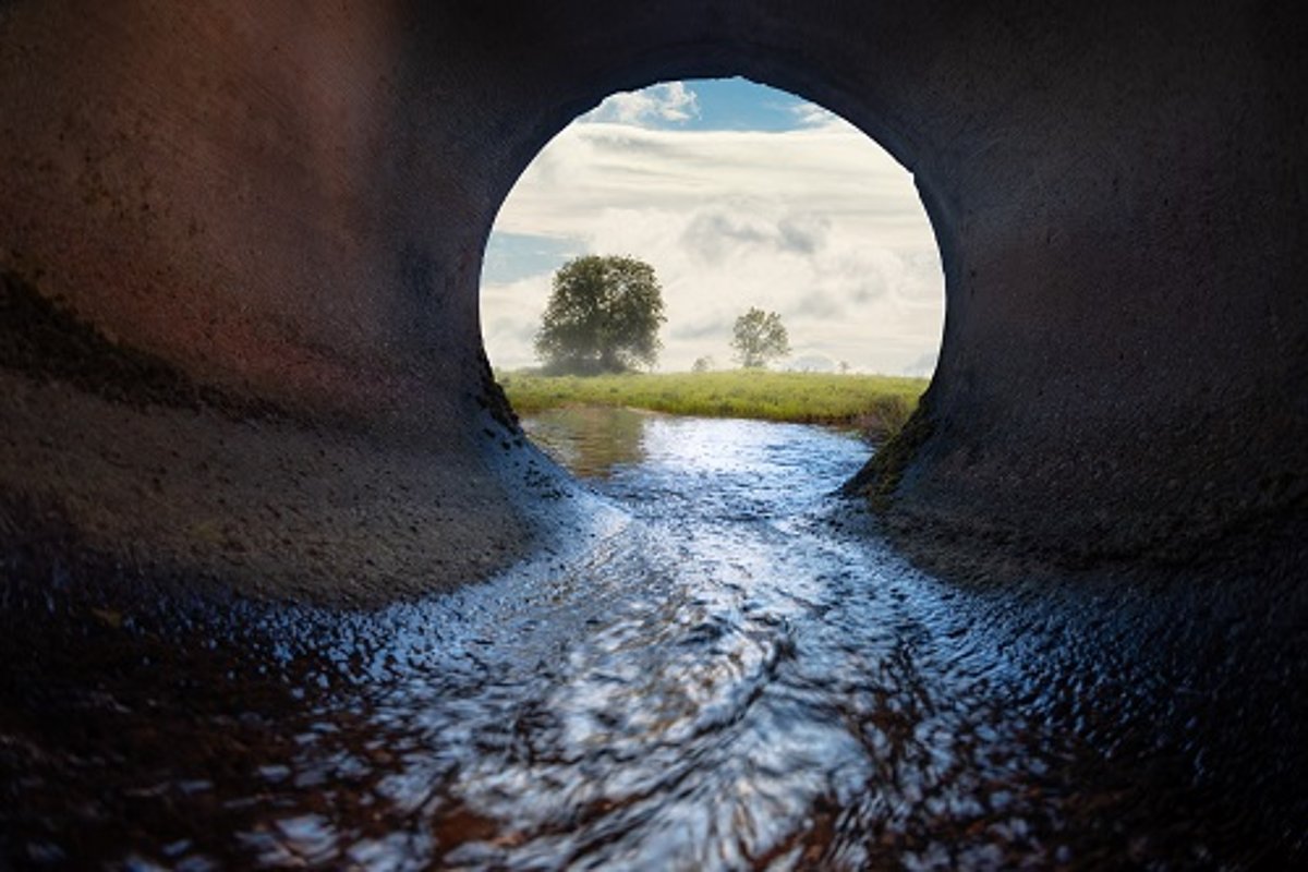 Wasser fließt aus einem dunklen Kanal nach draußen