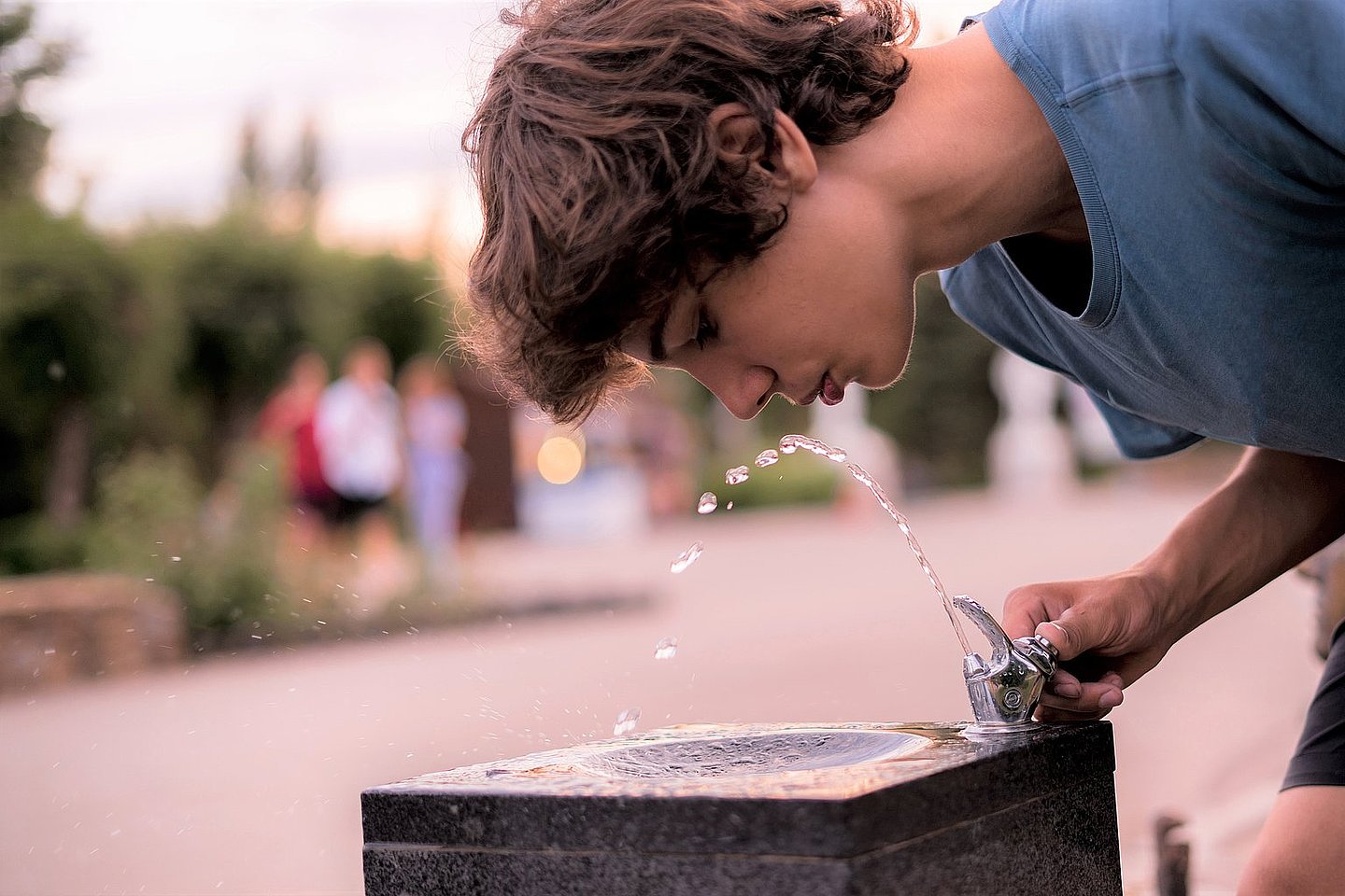 Junger Mann trinkt an Trinkbrunnen
