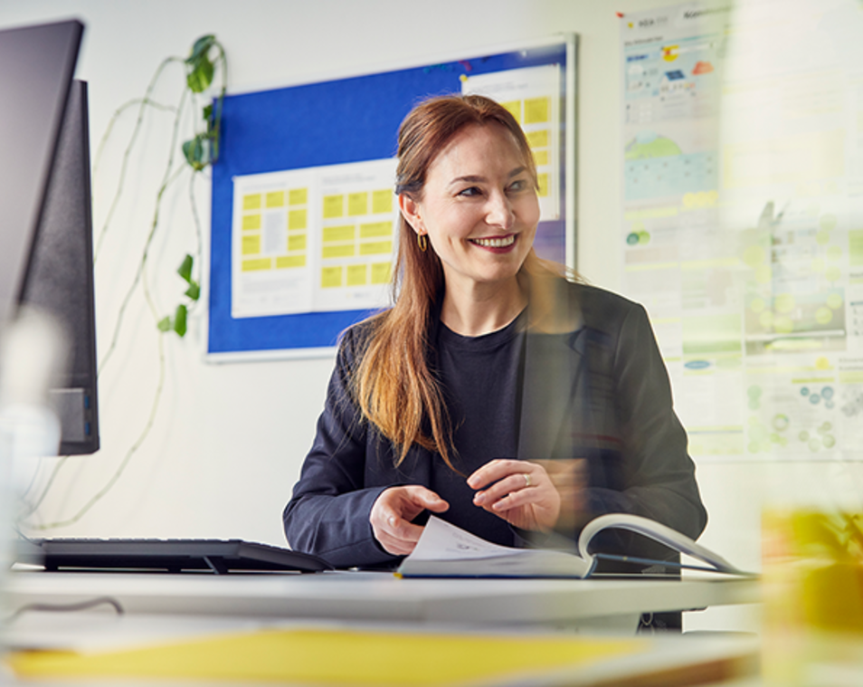Frau, die am Schreibtisch sitzt und Beratungsunterlagen durchschaut