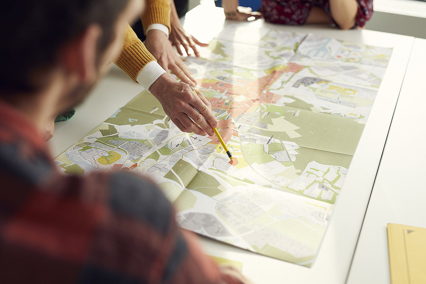 Blick auf einen Stadtplan mit Menschen am Tisch
