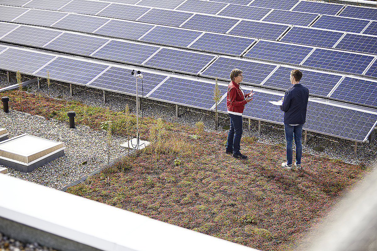 Zwei Personen beraten sich vor einer Photovoltaik-Anlage