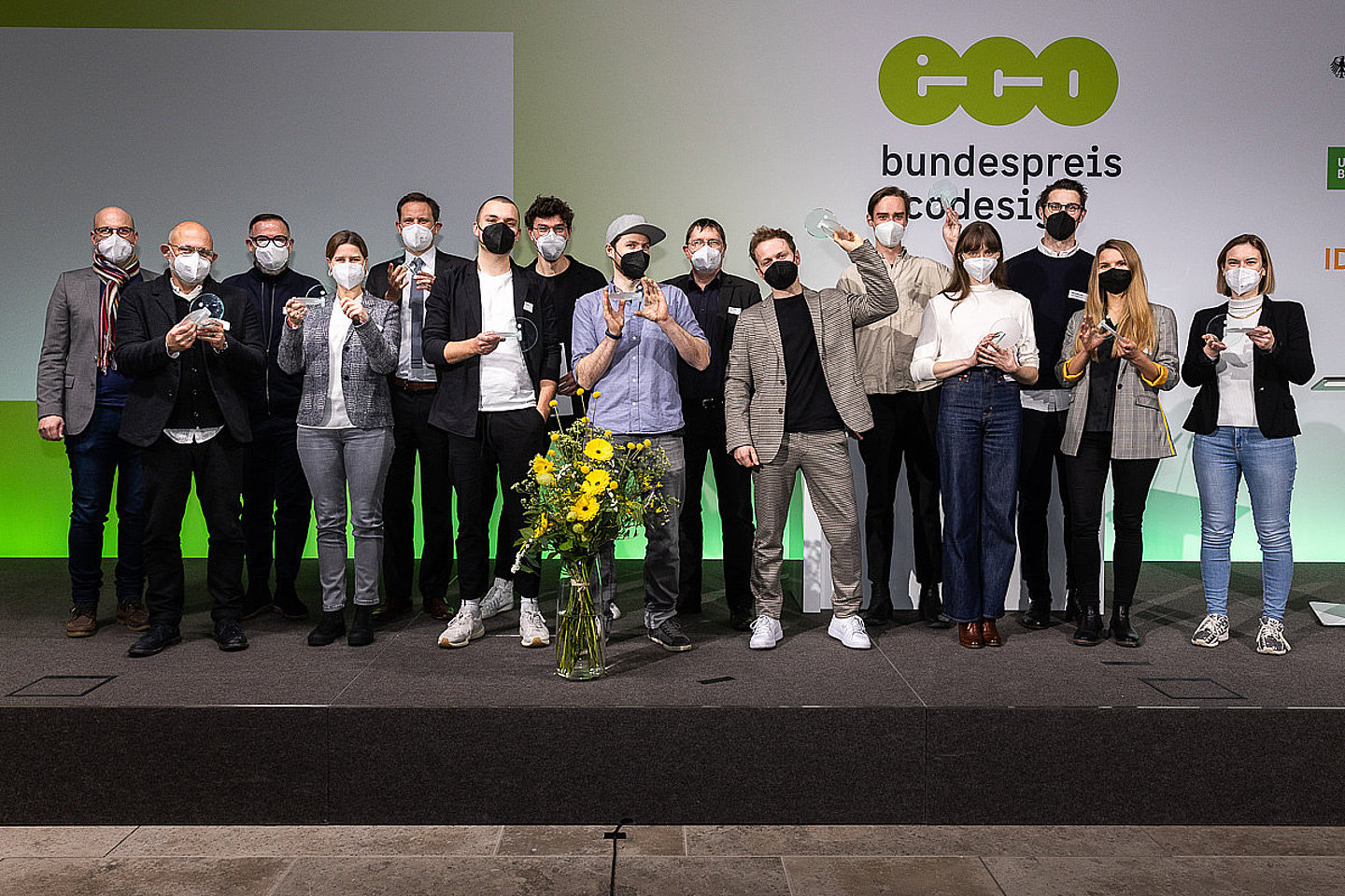 Foto der Preisträgerinnen und Preisträger des Bundespreises Ecodesign 2021, Alle Siegerinnen und Sieger stehen auf der Bühne mit einem Preis in der Hand