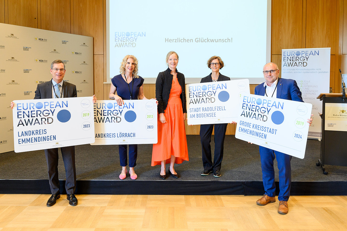 Drei Frauen und zwei Männer stehen auf einer Bühne. Vier Personen halten das Schild European Energy Award hoch.