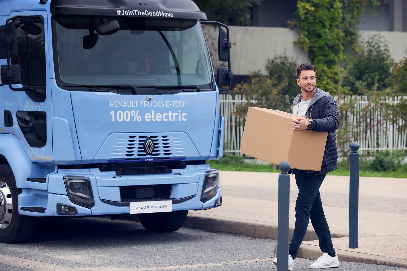 Logistikmitarbeiter mit Paket vor Elektro-Lkw
