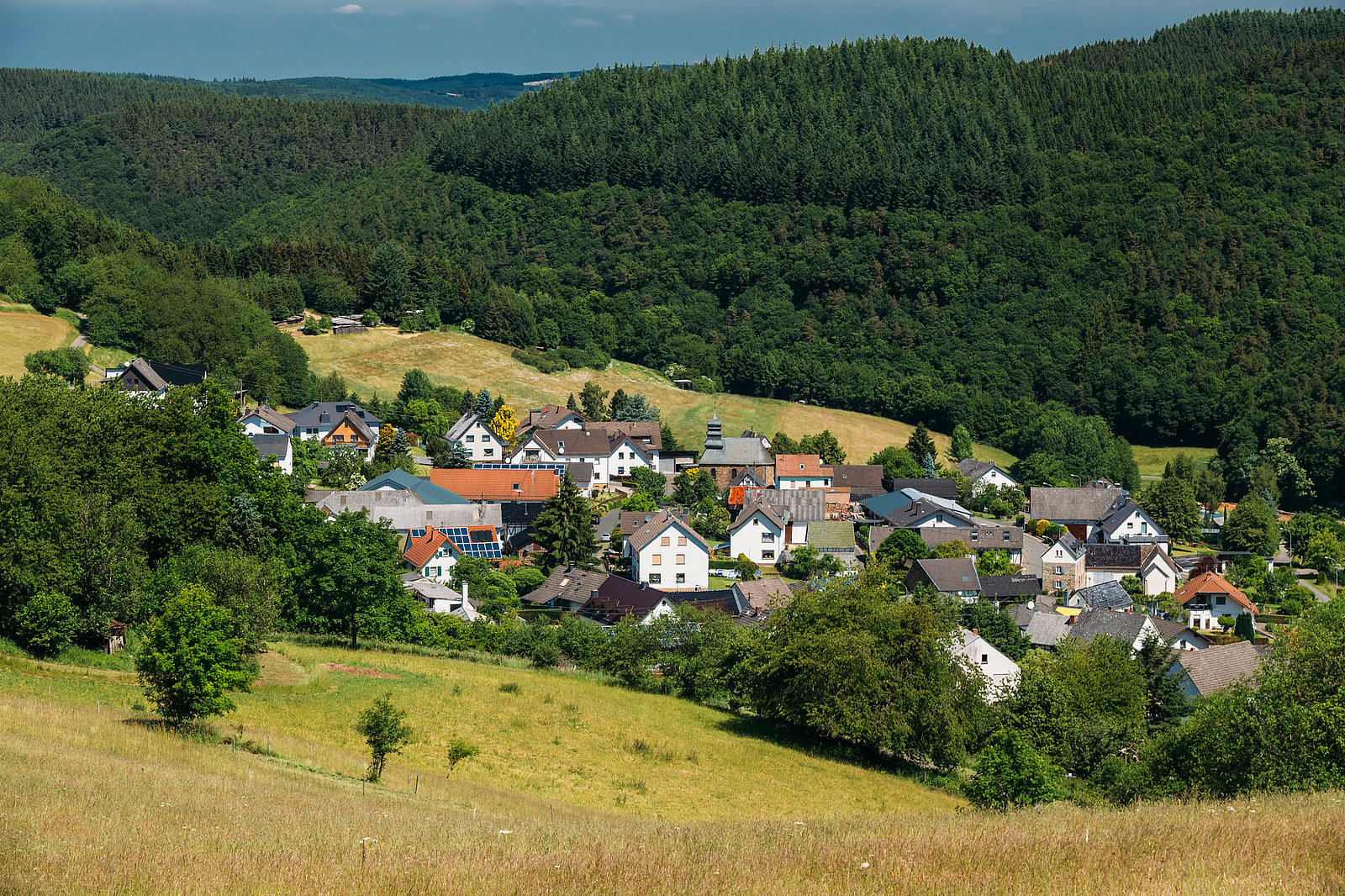 Dorf zwischen Hügeln Dorf zwischen Hügeln neben Wald