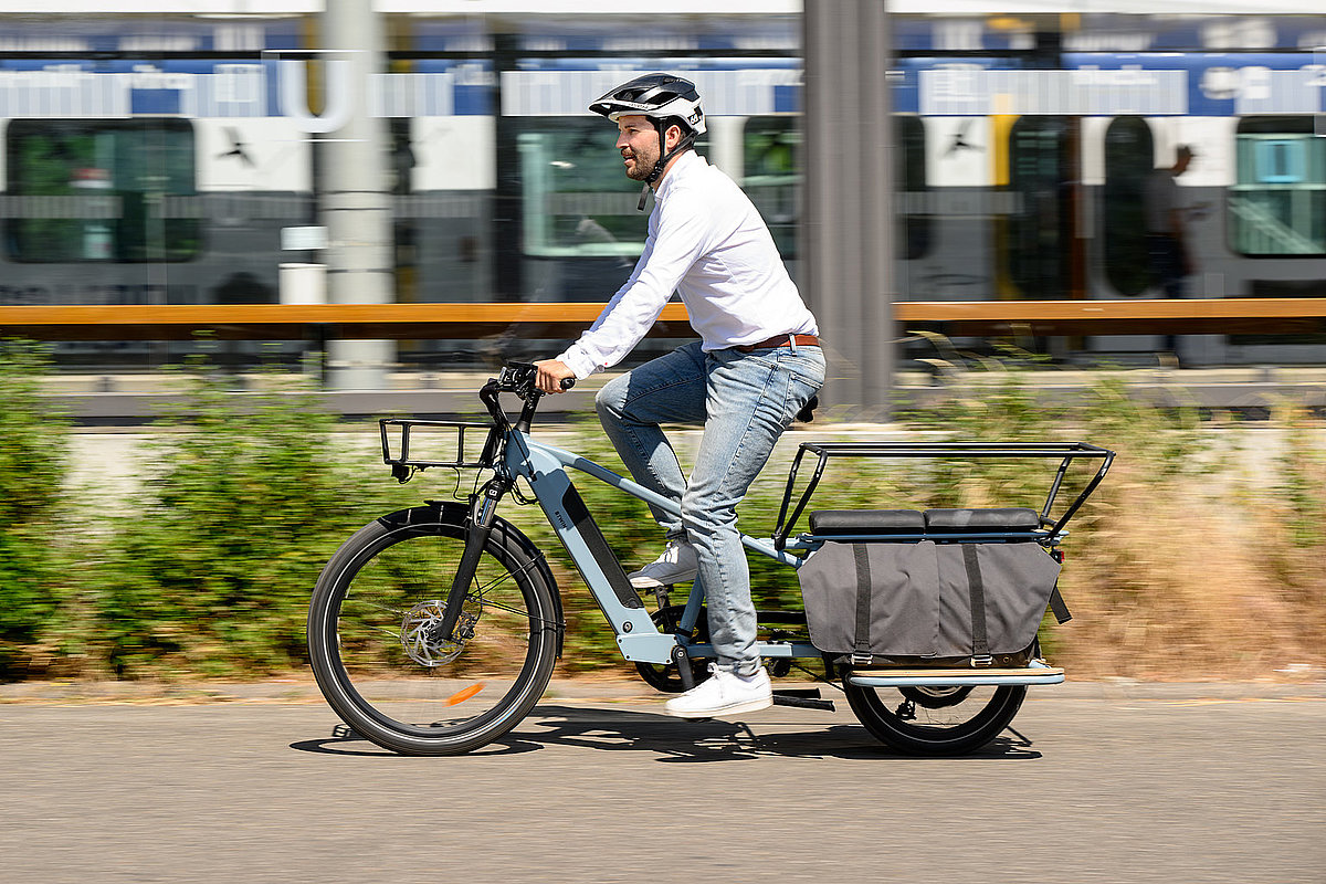 Mann auf Lastenrad vor U-Bahn