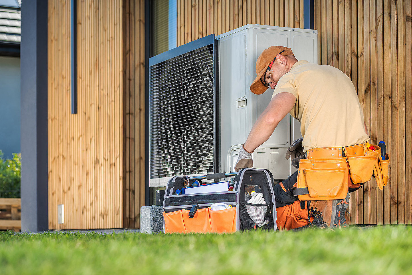 Mann installiert Wärmepumpe an Haus