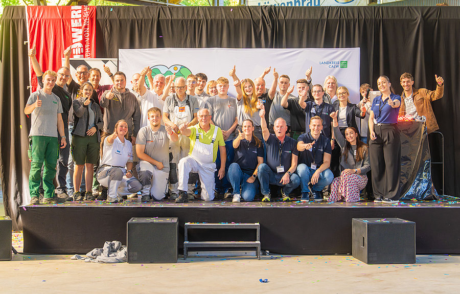 Etwa 40 Schülerinnen und Schüler winken von einer Bühen herab