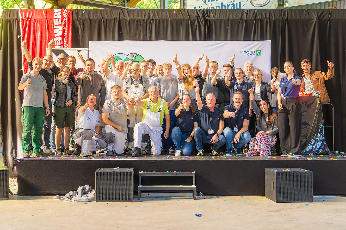 Etwa 40 Schülerinnen und Schüler winken von einer Bühen herab