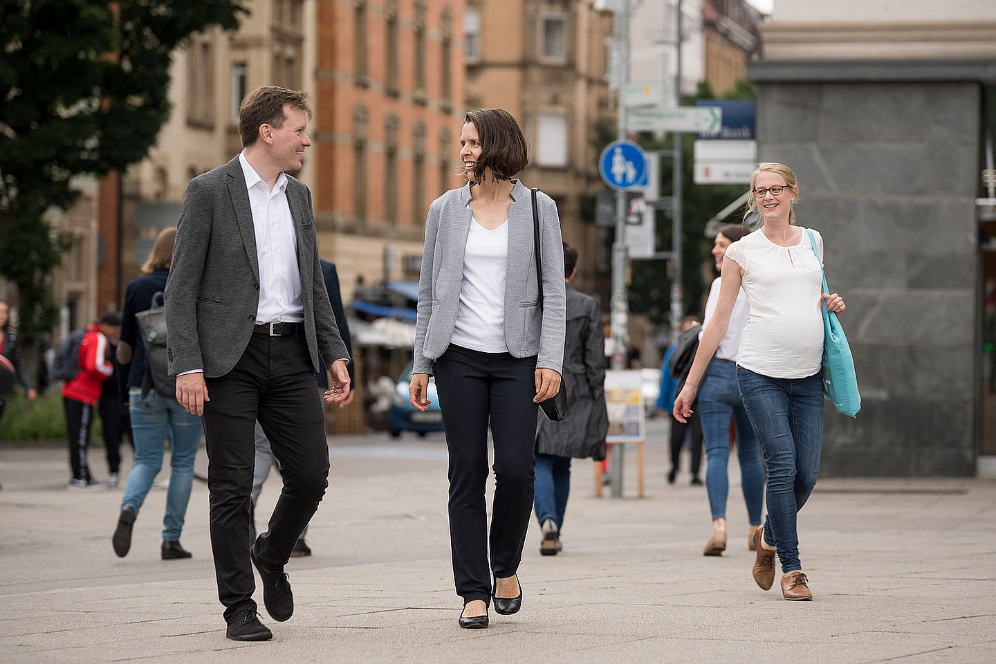 Mehrere Personen gehen in einer Fußgängerzone spazieren und unterhalten sich.