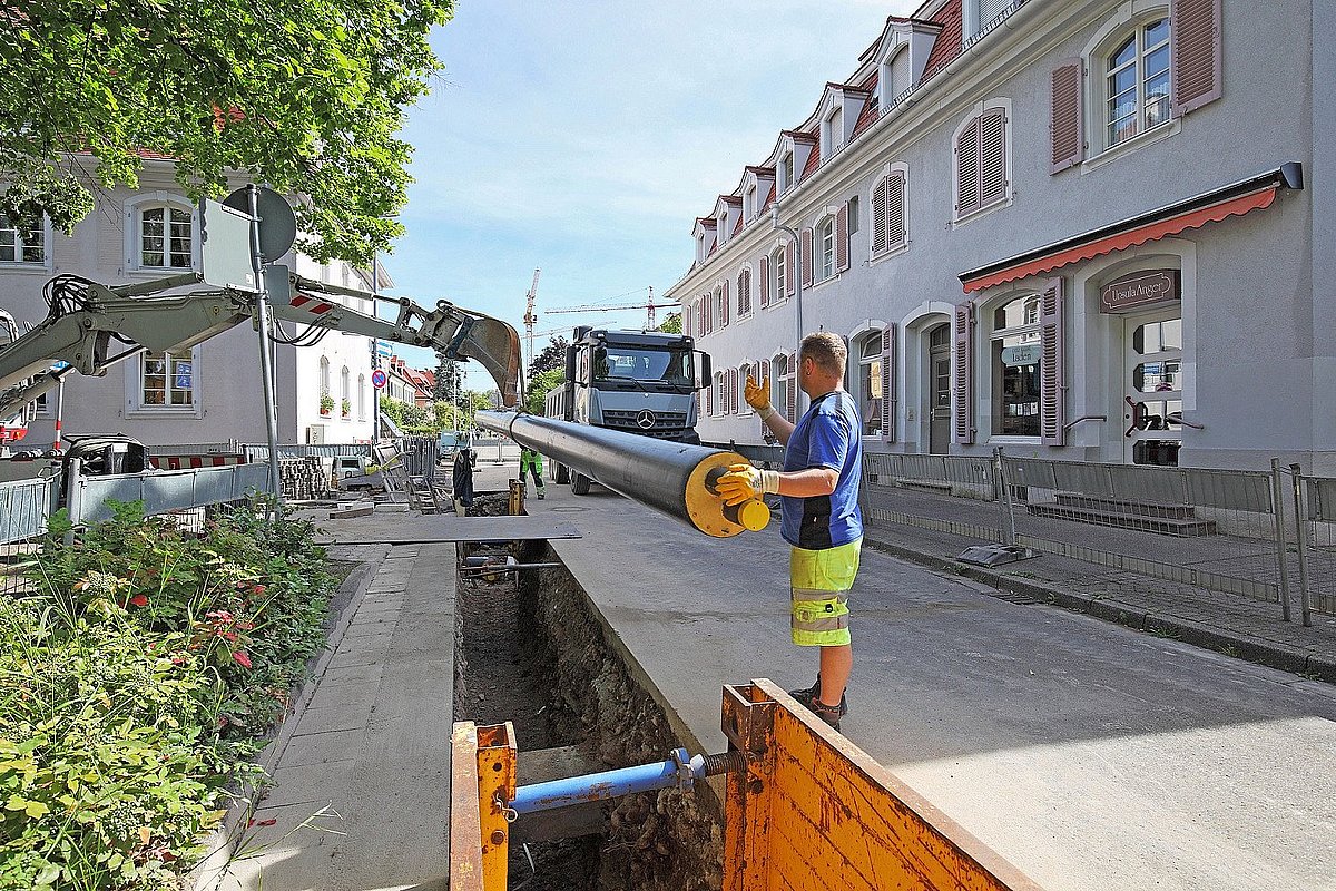 Mann verlegt Nahwärmerohr in Straße