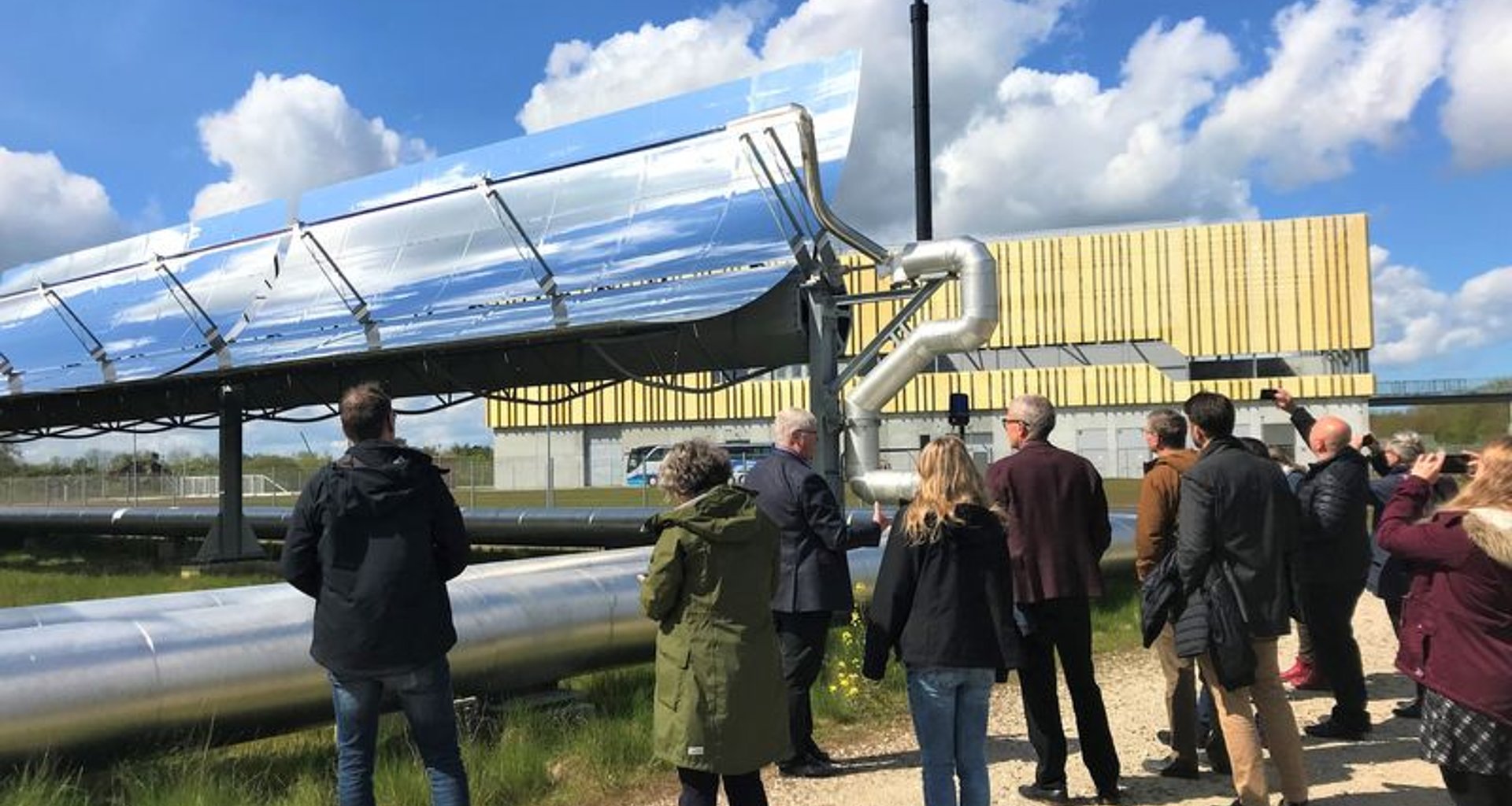 Das Foto zeigt eine Gruppe Menschen, die ein Parabolrinnen-Solarthermiemodul betrachtet.