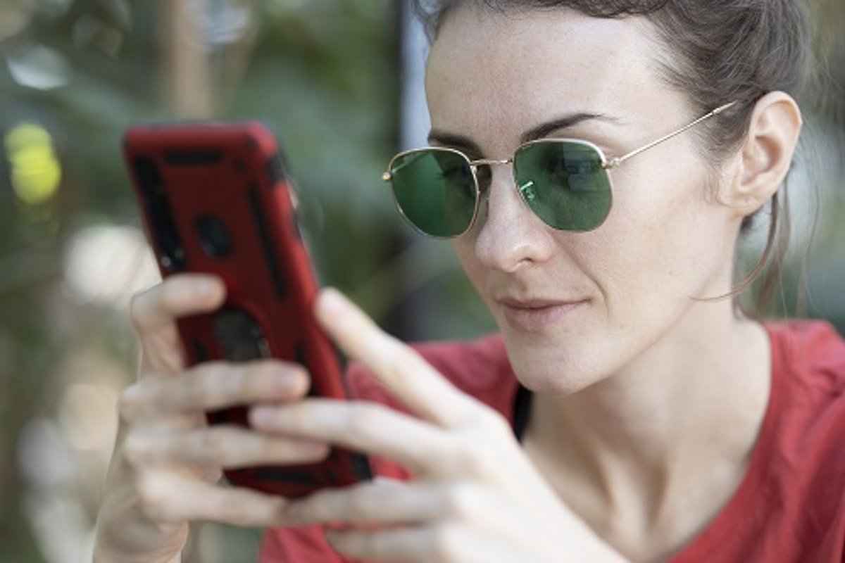 Frau mit Sonnenbrille sucht auf dem Smartphone