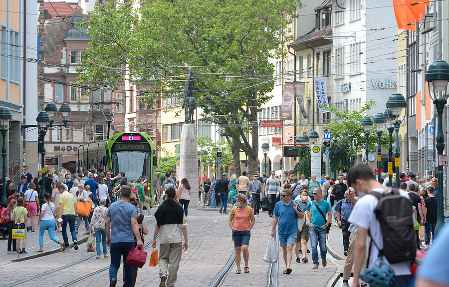 Menschen in Innenstadt mit Straßenbahn und Bushaltestelle