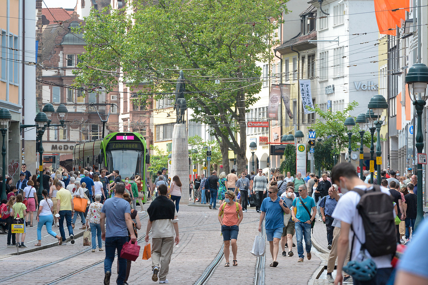 Menschen in Innenstadt mit Straßenbahn und Bushaltestelle
