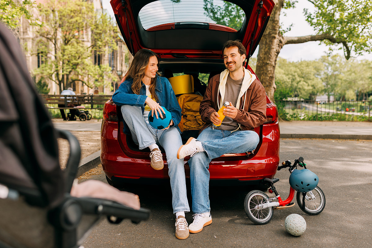 Kampagnen-Motiv Familie Carsharing Eltern mit Kinderfahrrad und Gepäck im Carsharing-Transporter