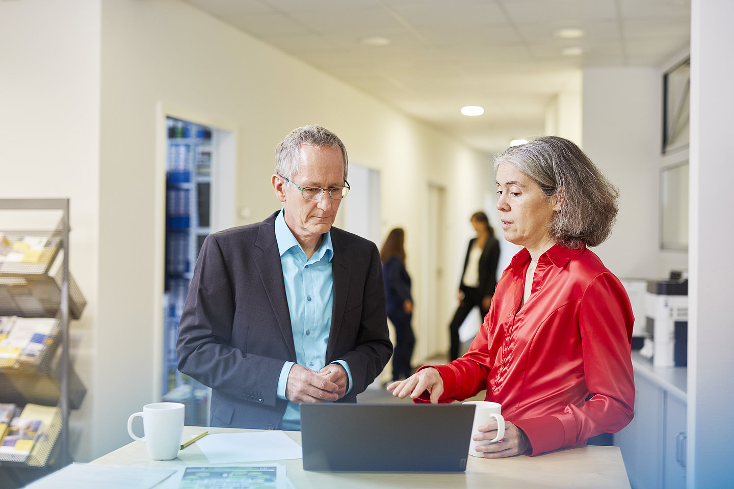 Mann und Frau unterhalten sich vor Laptop in einem Büro-Entree