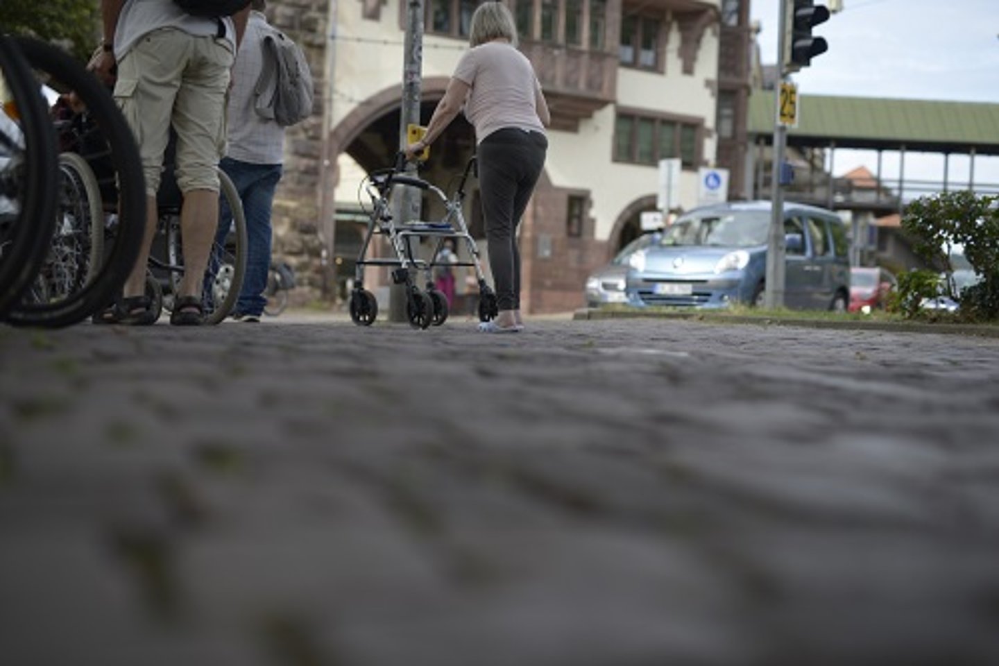 Bild vom Bürgersteig mit Seniorin an Gehhilfe