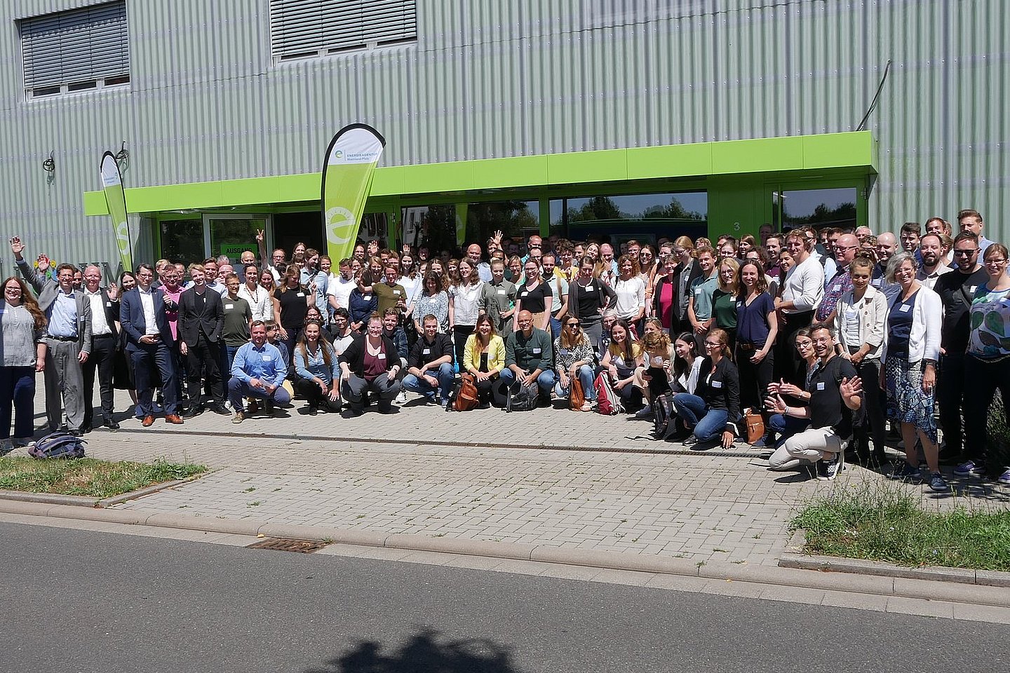 Eine große Gruppe von Menschen steht im Freien vor einem Gebäude