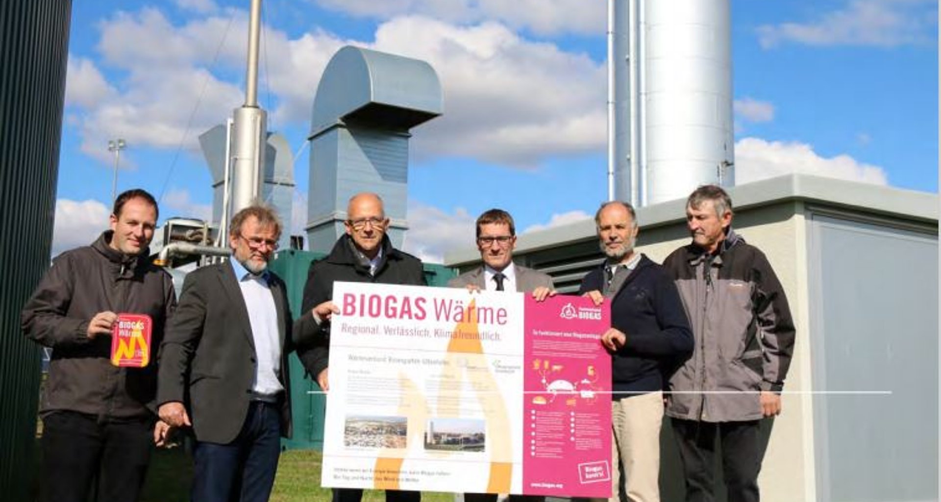 sechs Männer halten ein Plakat mit der Aufschrift "Biogas Wärme" in den Händen.