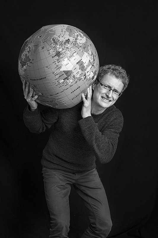 Schwarz-Weiß Foto von Lorenz Haublein wie er eine aufgeblasene Weltkugel auf den Schultern trägt.