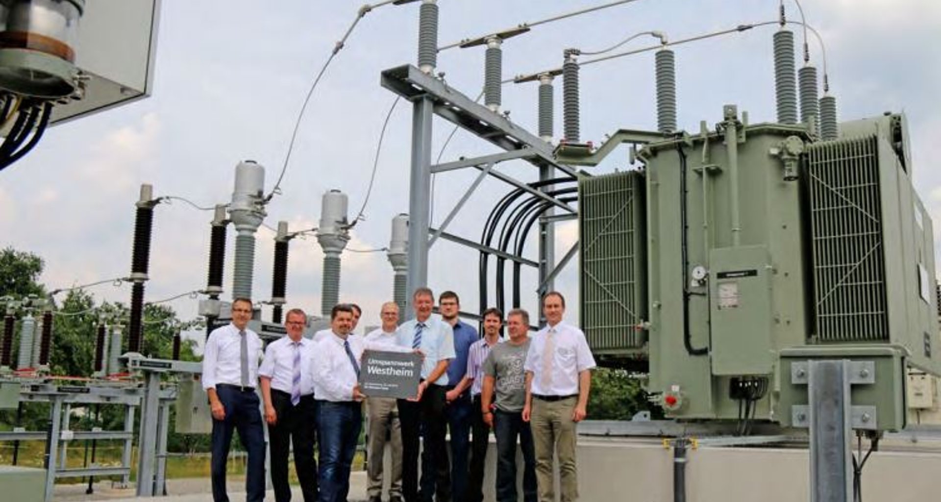 Foto zeigt zehn Männer vor dem neuen Umspannwerk.