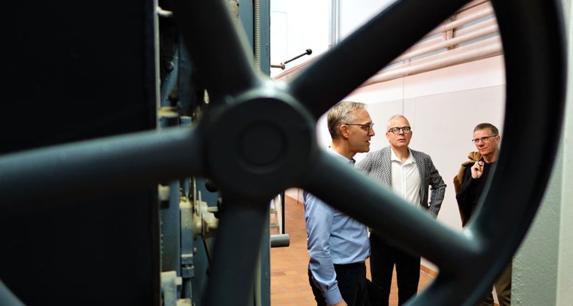 Man sieht drei sich unterhaltende Männer, aufgenommen durch ein Ventilrad.