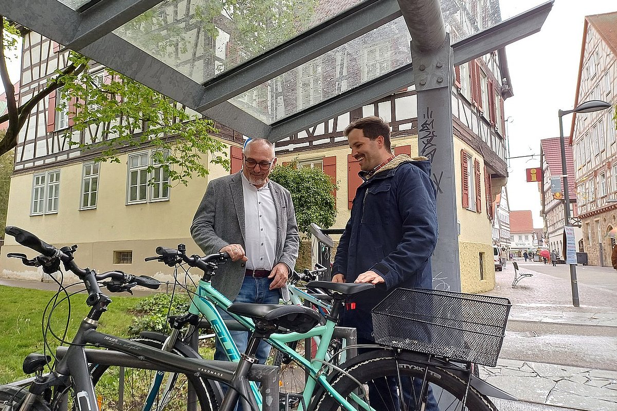 zwei Männer stehen an einem Fahrradständer vor einer Fußgängerzone