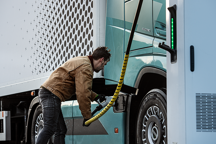 Ein Mann lädt einen E-LKW an einer Ladesäule