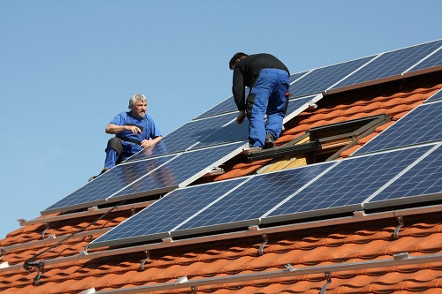 Zwei männer montieren Solarzellen auf einem Hausdach