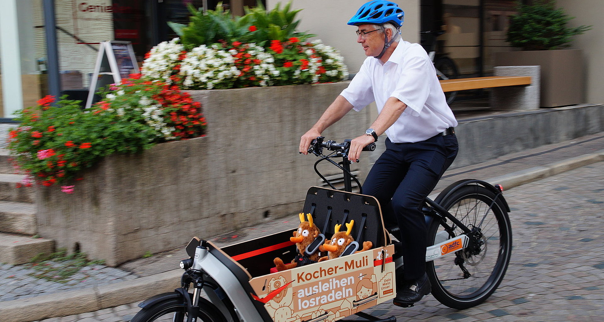 Oberbürgermeister Hermann-Josef Pelgrim fährt ein Elektrolastenrad mit der aufschrift "Kocher Muli, ausleihen und radeln"