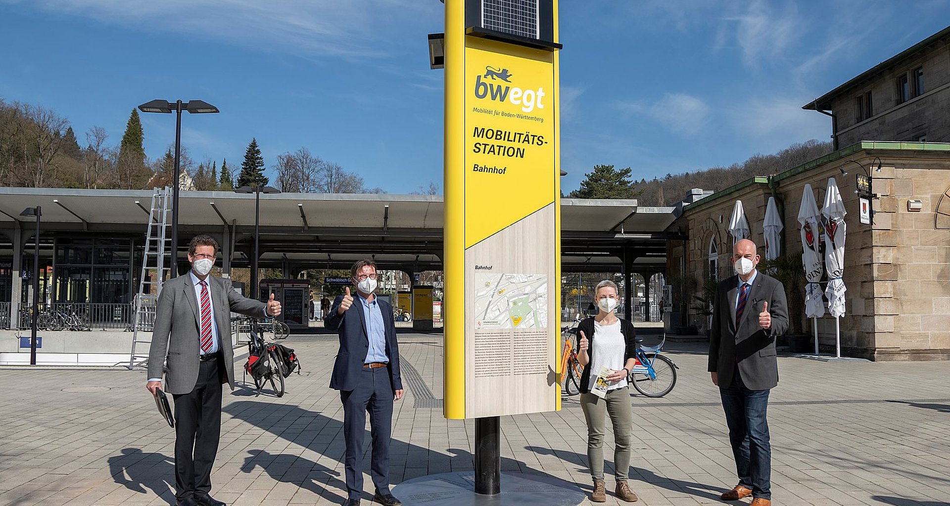 vier Menschen enthüllen auf vor dem Bahnhof in Schwäbisch Gmünd eine Mobilitätssäule.