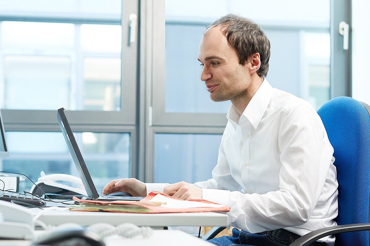 Mann sitzt am Schreibtisch mit Laptop