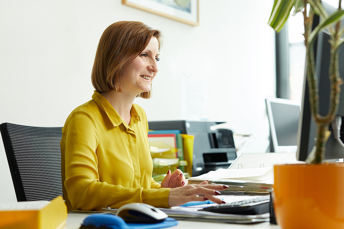 Frau sitzt am PC am Schreibtisch