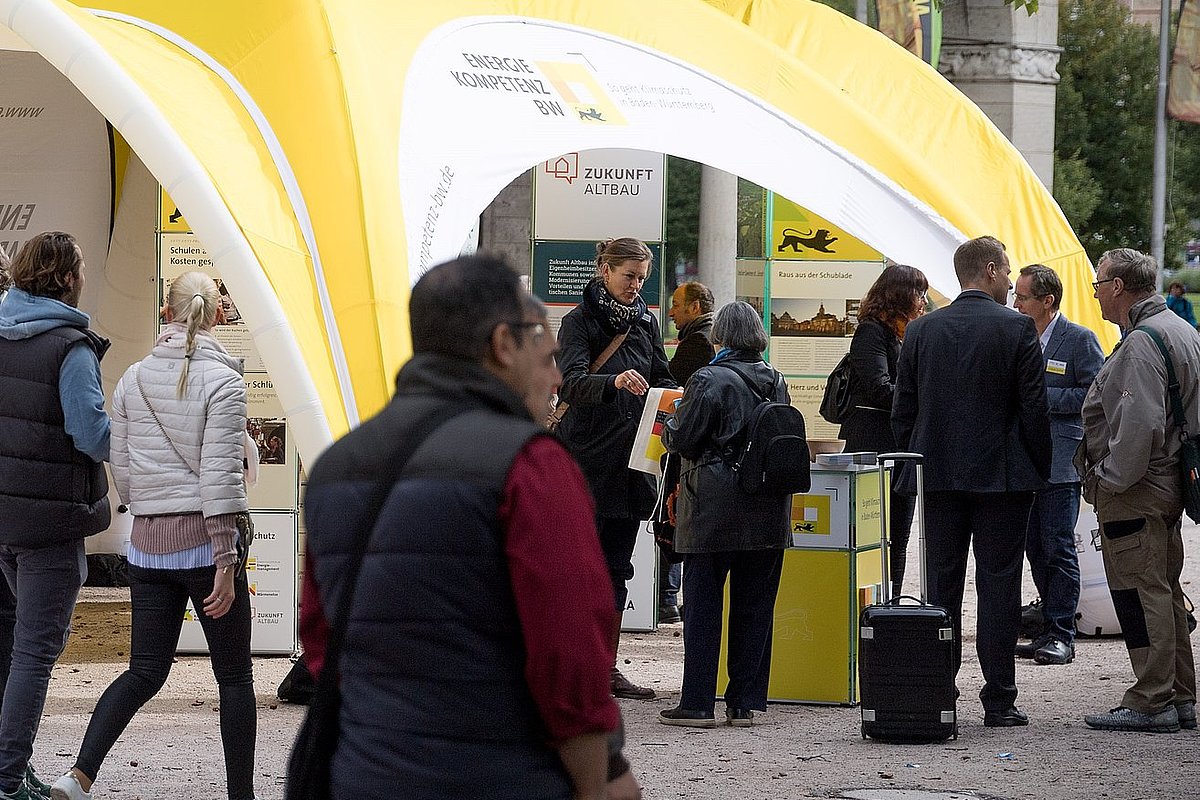 Menschen sprechen an einem Infostand miteinander