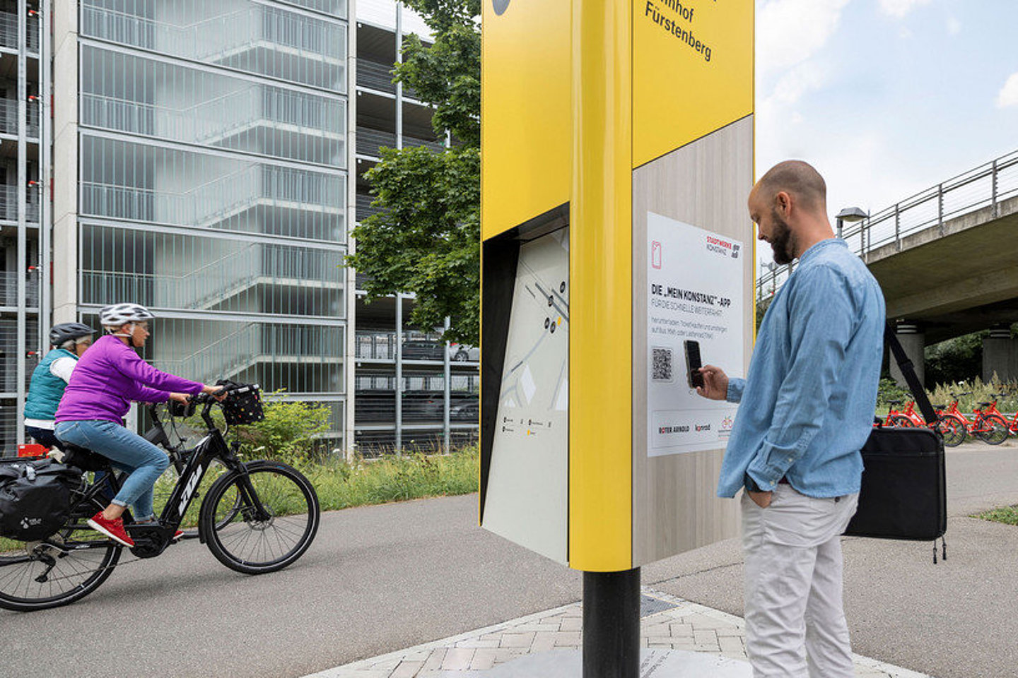 Radfahrende und Mann an Mobilitätssäule