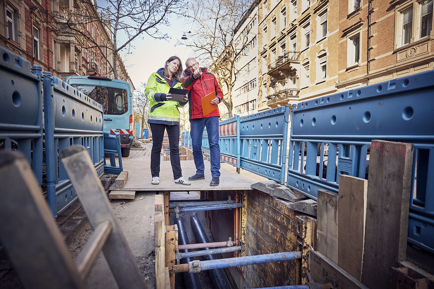 Mann und Frau stehen am Rande einer Fernwärmebaustelle und beraten sich.