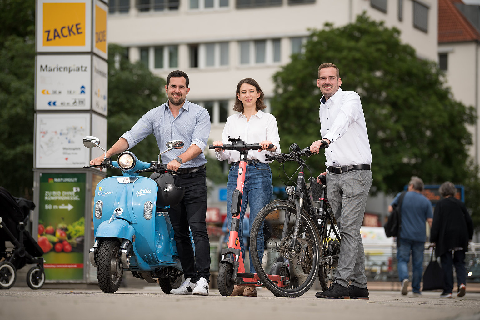 Daniel Schramek, Natalia Mill und Marc Schleehauf mit E-Moped, -Roller und -Fahrrad auf dem Marienplatz Stuttgart