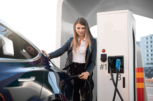 Junge Frau lädt Elektro-Auto an Schnellladesäule