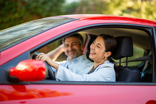 Mann und Frau sitzen im Auto, lächelnd