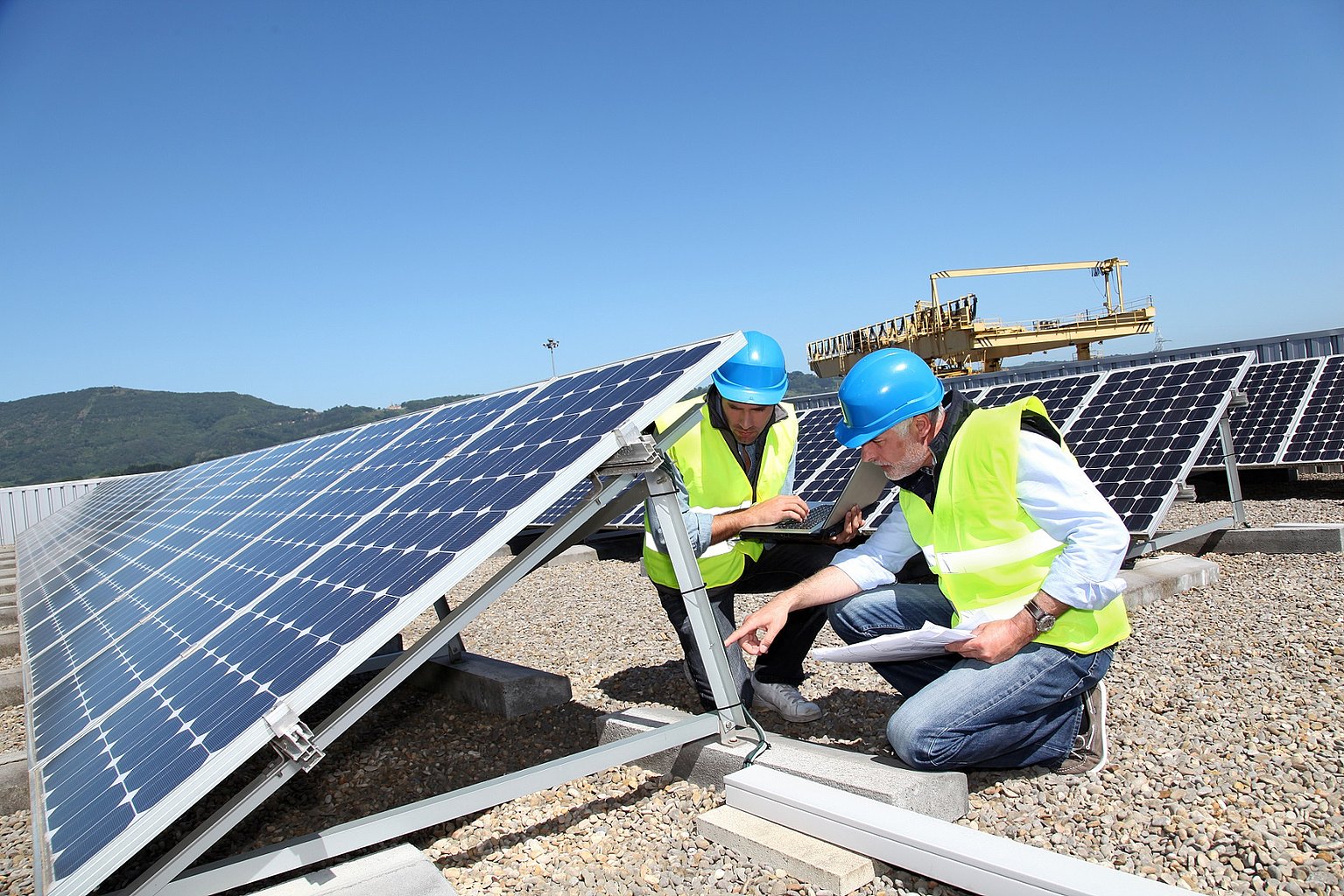 Zwei Männer prüfen eine Solaranlage auf einem Dach